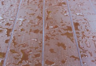 Close-up of a wooden deck with scattered raindrops reflecting light.